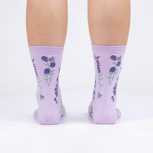A pair of lavender crew socks with a pattern of purple flowers and yellow bees.