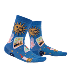 Lifestyle shot showing the 'It's In The Cards Shimmer' socks on a person's legs. The socks are blue with celestial and tarot-inspired designs.