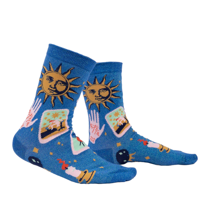 Lifestyle shot showing the 'It's In The Cards Shimmer' socks on a person's legs. The socks are blue with celestial and tarot-inspired designs.