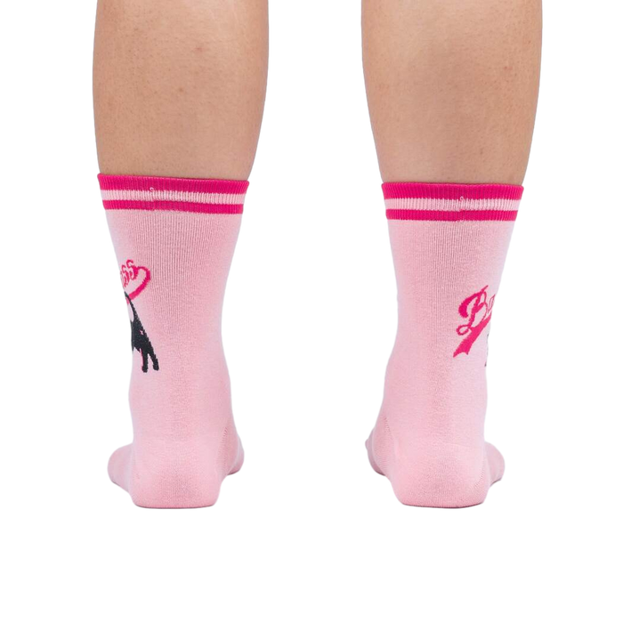 Rear view of a person's legs wearing pink 'Bad Ass Cat' socks, showing the full design on the back of the socks.