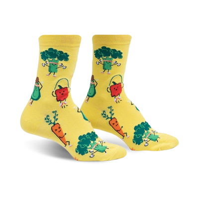 plant powered crew socks for women, featuring yellow socks with a pattern of exercising vegetables such as carrots doing yoga, aerobics avocados, and jogging red peppers. 