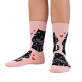 Lifestyle shot showing the socks on a person's legs. Pale pink socks with black cat design.