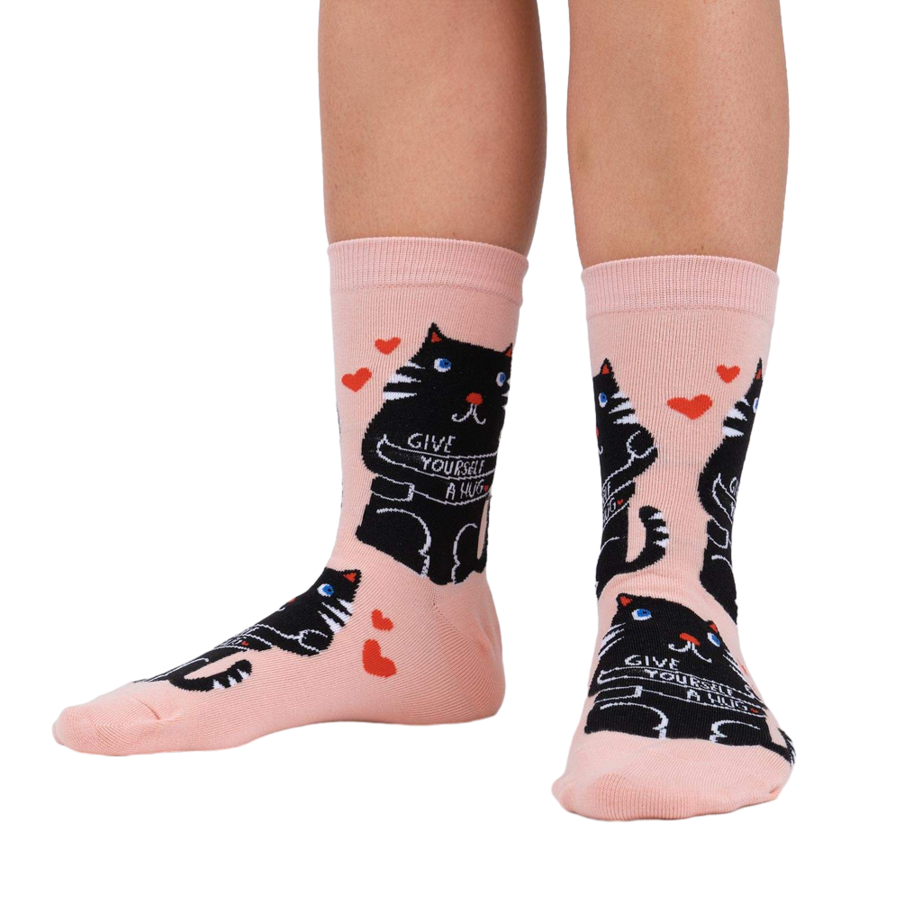 Lifestyle shot showing the socks on a person's legs. Pale pink socks with black cat design.