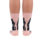 Back view of the socks on a person's legs. The socks are pale pink with black cats and hearts.