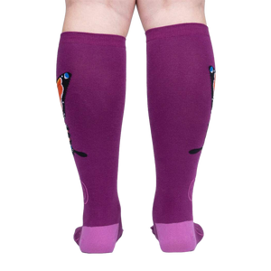 Back view of a person wearing purple knee-high socks with an orange butterfly design.