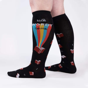 Black knee-high socks with a repeating pattern of red, orange, yellow, green, blue and purple books. The words 