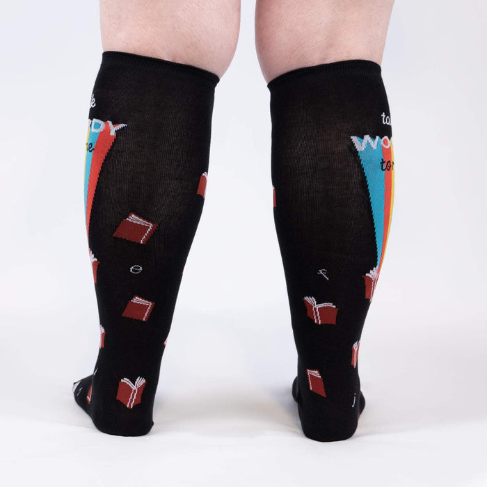 Black knee-high socks with a repeating pattern of red, orange, yellow, green, blue and purple books. The words 