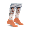 Pair of women's knee-high socks. Light blue background with two Frida Kahlo self-portraits, peach-colored cuffs.  Detailed artwork.