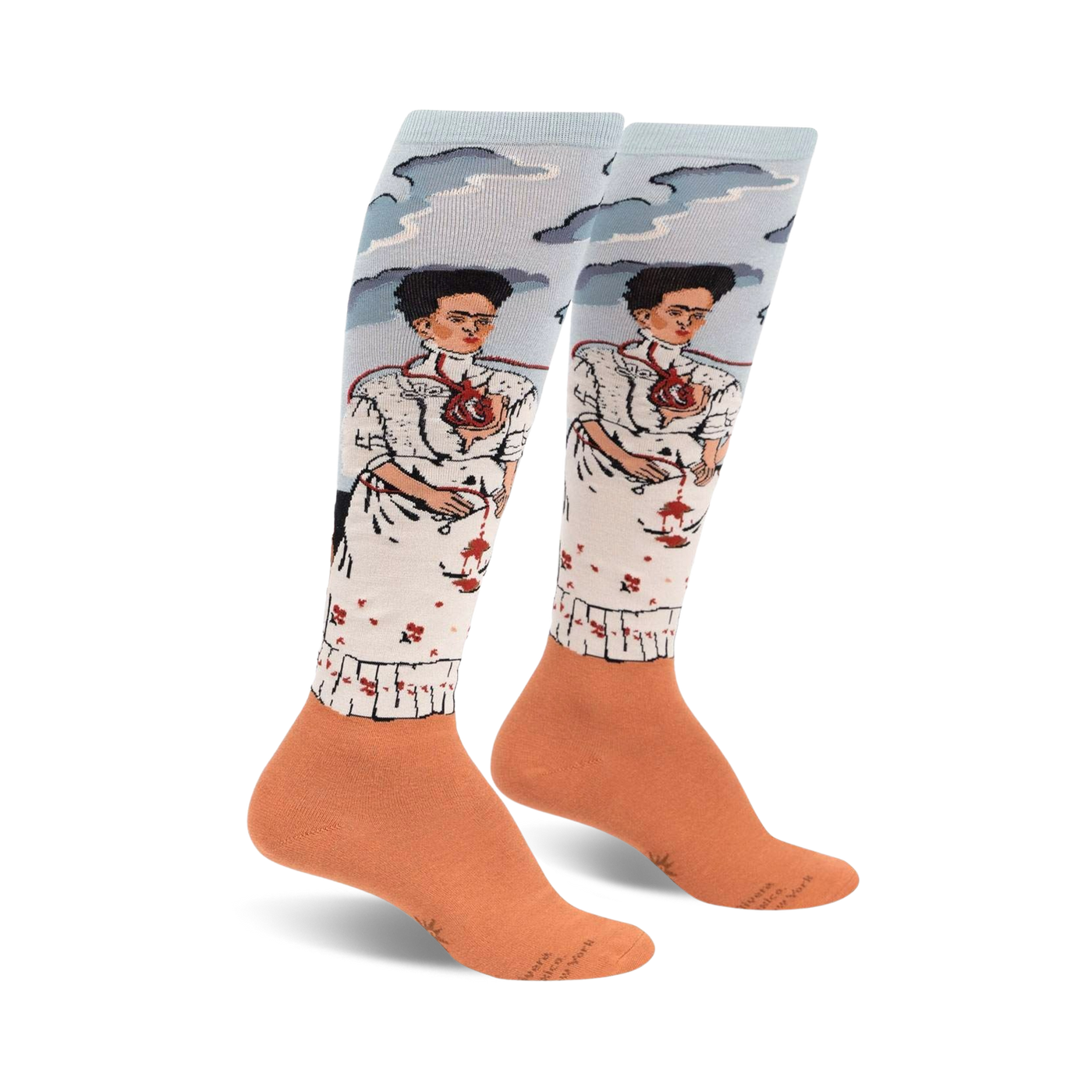 Pair of women's knee-high socks. Light blue background with two Frida Kahlo self-portraits, peach-colored cuffs.  Detailed artwork.