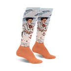 Pair of women's knee-high socks. Light blue background with two Frida Kahlo self-portraits, peach-colored cuffs.  Detailed artwork.