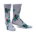 Pair of grey crew socks featuring a repeating pattern of Bigfoot riding a teal T-Rex and holding a mug. 