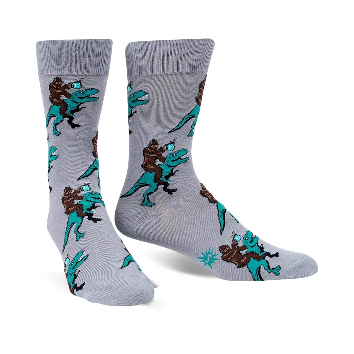 Pair of grey crew socks featuring a repeating pattern of Bigfoot riding a teal T-Rex and holding a mug. 