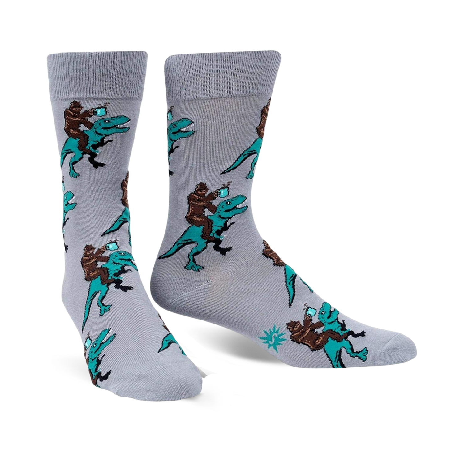 Pair of grey crew socks featuring a repeating pattern of Bigfoot riding a teal T-Rex and holding a mug. 