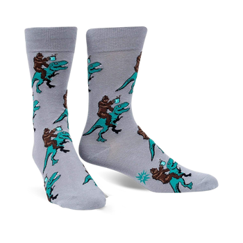 men's gray crew socks featuring bigfoot riding dinosaurs in black, brown, and teal.  