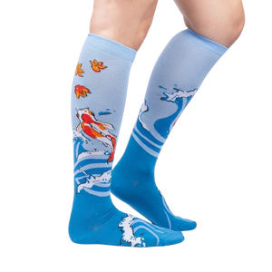 A pair of blue knee-high socks with a pattern of koi fish and maple leaves.