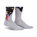 Pair of grey crew socks with a design featuring an astronaut painting planets onto a dark background. 