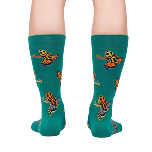 A person's legs from the knees down wearing green socks with a pattern of orange and black frogs.