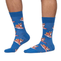 Lifestyle shot: Person wearing blue crew socks with a pattern of corgis surfing.