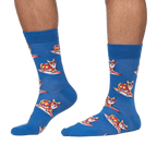 Lifestyle shot: Person wearing blue crew socks with a pattern of corgis surfing.