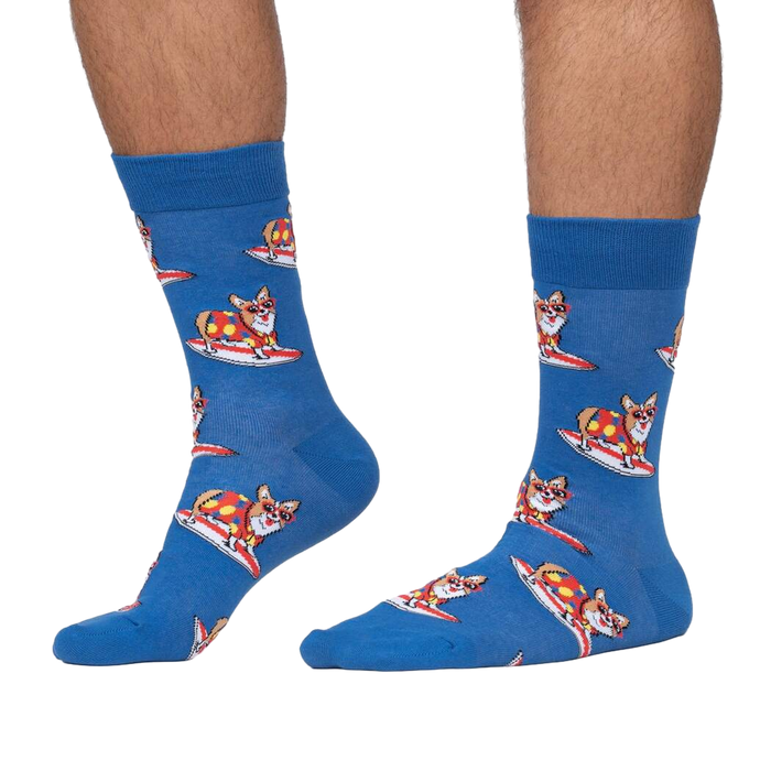 Lifestyle shot: Person wearing blue crew socks with a pattern of corgis surfing.