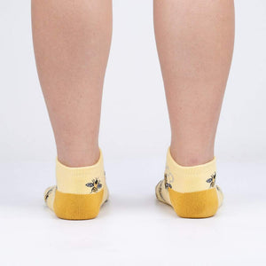A pair of yellow socks with a pattern of bees and beehives.