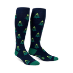 Pair of navy blue knee-high socks with a repeating pattern of green Bigfoot figures hidden amongst lime green and darker green Christmas trees.