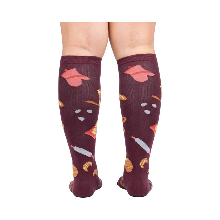 Back view of 'Bake at 350' burgundy knee-high socks on a person's legs against a white background.