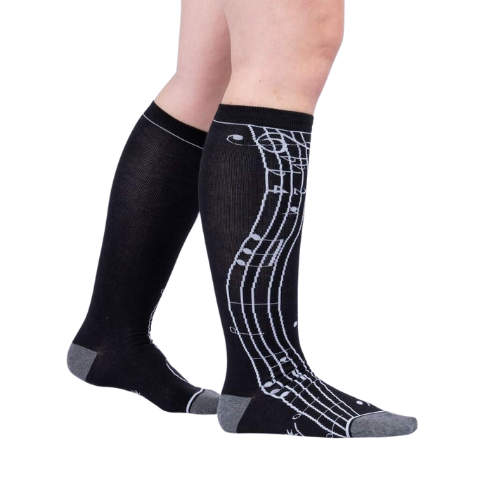 A pair of black knee-high socks with a musical notes pattern in gray.
