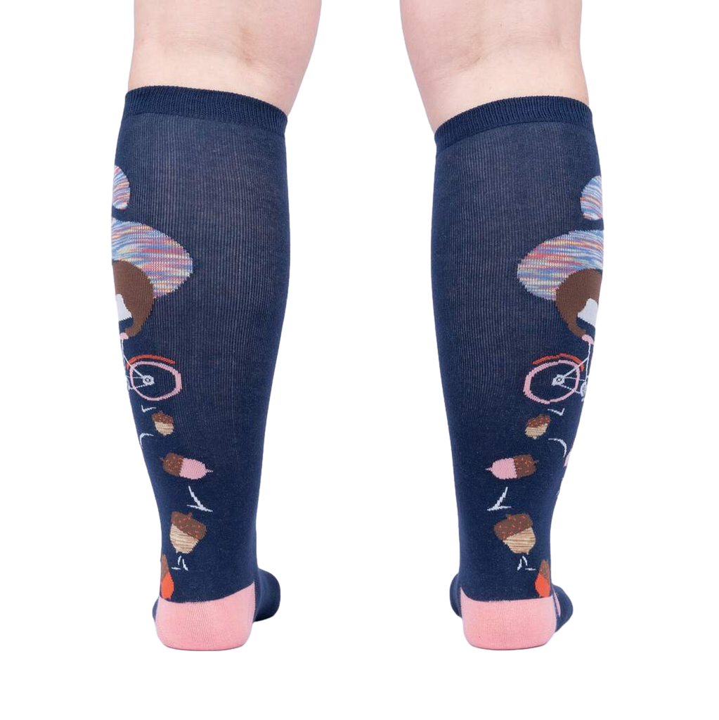 Rear view of the 'Feeling Squirrelly' knee-high socks on a person's legs, highlighting the full design on both socks.