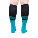 Rear view of the socks highlighting the full design. The socks are teal and black and glow in the dark.