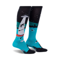 Pair of teal and black knee-high socks depicting a humorous alien abduction scene on a lake at night.  The socks glow in the dark.