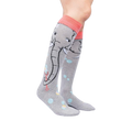 Lifestyle shot: Model wearing a pair of grey and coral knee-high socks with an elephant and bubble design.