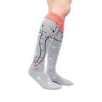 Lifestyle shot: Model wearing a pair of grey and coral knee-high socks with an elephant and bubble design.