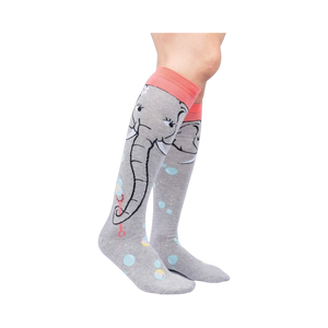 Lifestyle shot: Model wearing a pair of grey and coral knee-high socks with an elephant and bubble design.