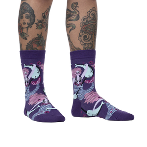 Lifestyle shot of a model wearing the Fin Friends socks, showcasing the socks' fit and pattern on legs with tattoos.