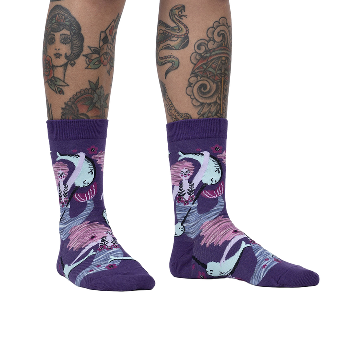 Lifestyle shot of a model wearing the Fin Friends socks, showcasing the socks' fit and pattern on legs with tattoos.