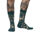 Lifestyle shot of model wearing teal crew socks with deer and flower design.