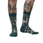 Lifestyle shot of model wearing teal crew socks with deer and flower design.