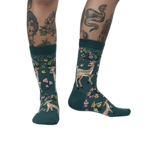 Lifestyle shot of model wearing teal crew socks with deer and flower design.