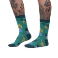 Lifestyle shot showing the Plant Mom socks on a woman's legs. The socks are green with a fun plant design.