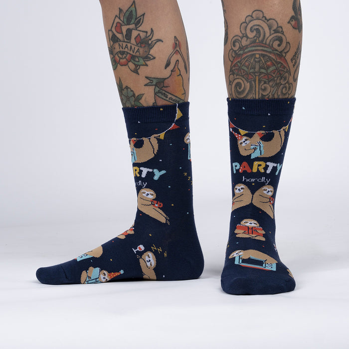 A pair of blue socks with a pattern of sloths wearing party hats and holding drinks. The socks have the words 