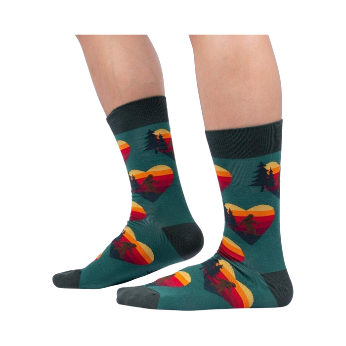 Lifestyle shot showing the socks on a person's legs; teal socks with Sasquatch and sunset heart design.