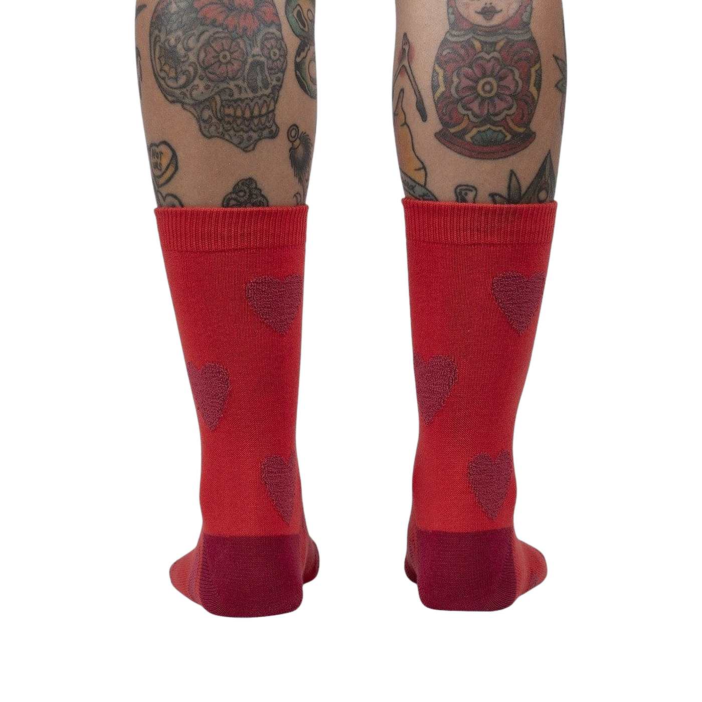 Back view of a person's legs wearing red crew socks with maroon fuzzy hearts.