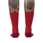 Back view of a person's legs wearing red crew socks with maroon fuzzy hearts.