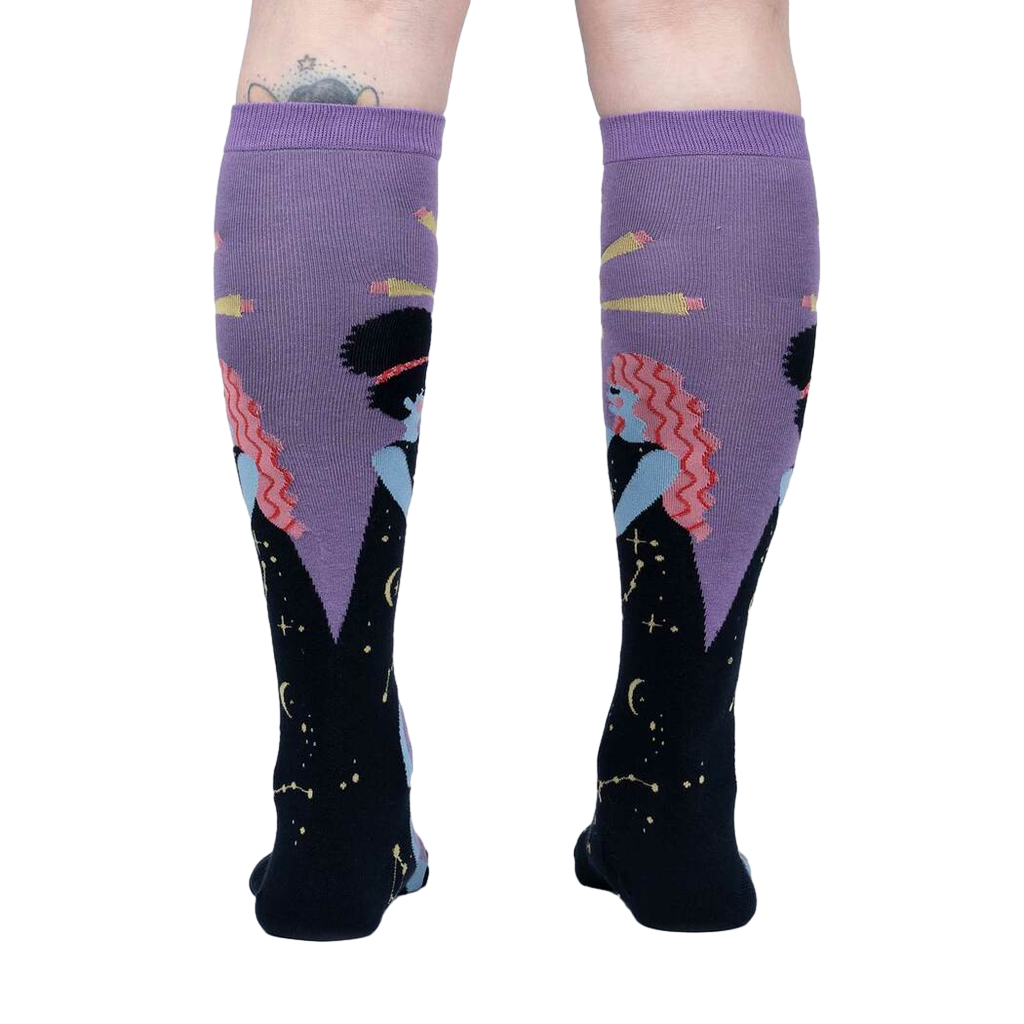 Rear view of model wearing a pair of Cosmic Connection knee-high socks.