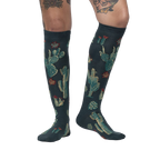 Lifestyle photo: Person wearing the Cactus Jungle knee-high socks, showing the socks on their legs.