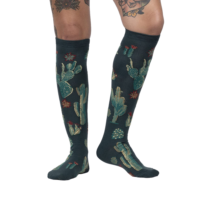 Lifestyle photo: Person wearing the Cactus Jungle knee-high socks, showing the socks on their legs.
