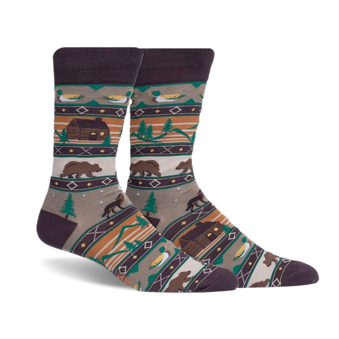 pair of socks featuring a cabin, bears, trees, and ducks in a woodland pattern. the socks are a brown, beige, green, and orange color. the socks are photographed from an angle with the right sock over the left sock.