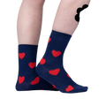 Close-up on a person's legs wearing navy blue crew socks with red fuzzy hearts.