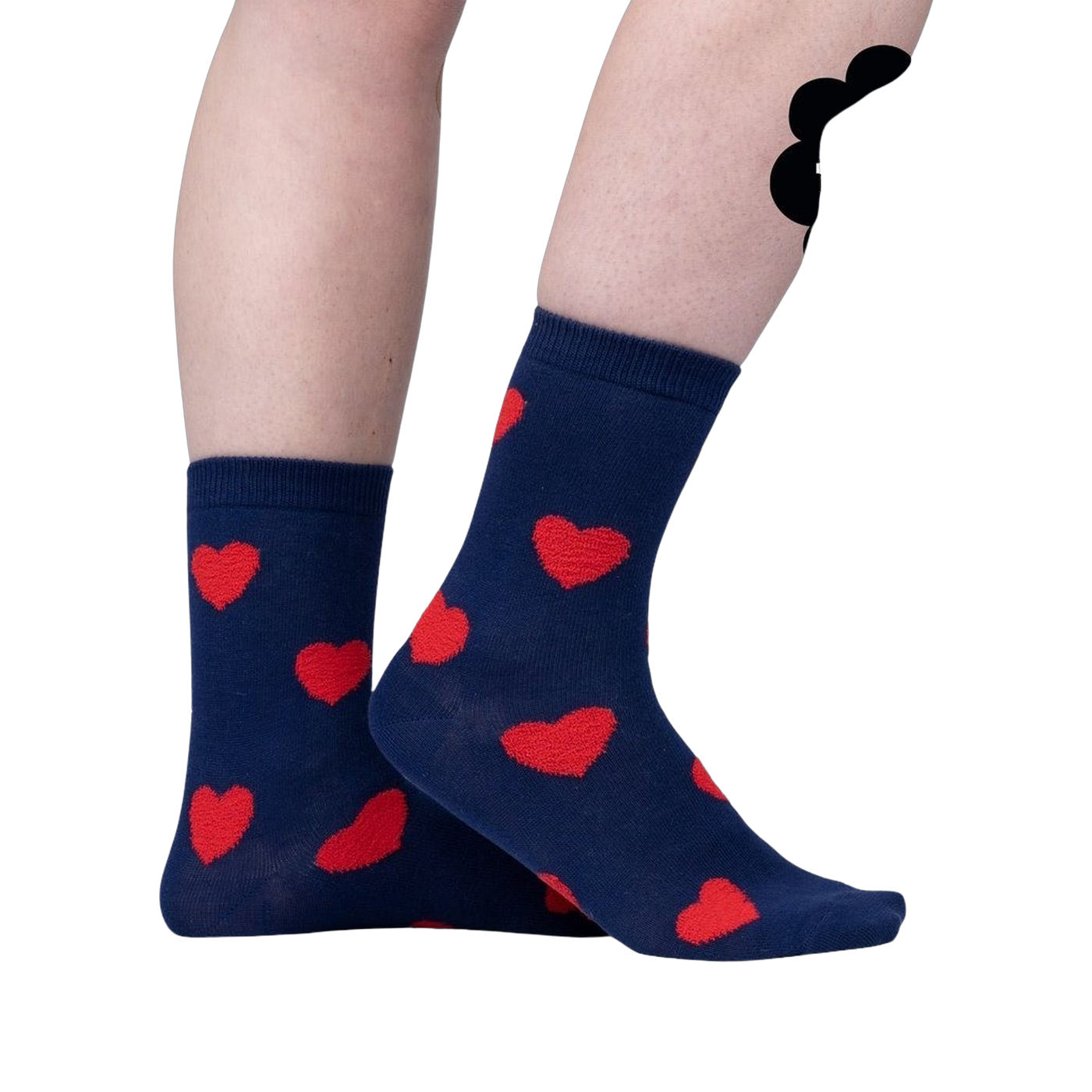 Close-up on a person's legs wearing navy blue crew socks with red fuzzy hearts.